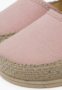 Różowe płócienne buty typu slip-on z plecionymi podeszwami z juty. Charakteryzują się gładką teksturą i minimalistycznym designem z delikatnym akcentem w postaci przeszycia.