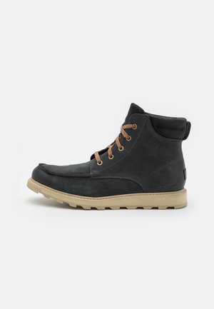 Black leather ankle boots with tan laces, rounded toe, and a contrasting rubber sole. Features stitching detail and supportive ankle design.