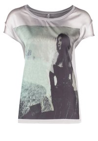 Camiseta de manga corta y corte holgado en tejido ligero. Presenta una gran impresión monocromática de una figura sobre un fondo texturizado.