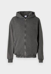 Šedá mikina na zips s kapucňou, vyrobená z jemného materiálu. Má predný zips, dve bočné vrecká a rebrované manžety a lem.