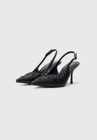 Escarpins slingback en cuir noir avec bouts pointus, laçage à l'avant, petits clous en argent sur les brides et fins talons aiguilles de hauteur moyenne.