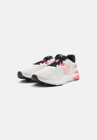 Hvite sportsko med svarte detaljer, rosa innslag, overdel i mesh, gummisåle og en polstret mellomsåle. Har PUMA-logo på siden.