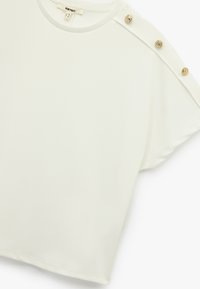 Witte short-sleeve top met een ronde hals en decoratieve gouden knopen op de schouders. Gladde textuur, ontspannen pasvorm en subtiele glans.