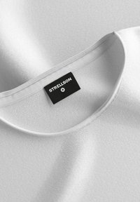 Weiße Baumwoll-T-Shirt mit weicher Textur, rundem Halsausschnitt und einem schwarzen "STRELLSON"-Label, das am Kragen genäht ist.
