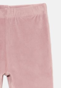 Rózsaszín bársonyos leggings sima textúrával, rugalmas derékkal és testhezálló fazonnal, puha felülettel és látható minták nélkül.