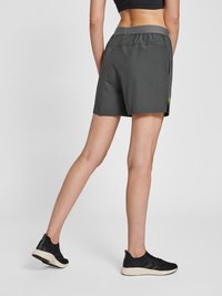 Grå träningsshorts med elastisk midja, sidfickor och en liten logodetalj. I kombination med svarta sportskor på ljus bakgrund.