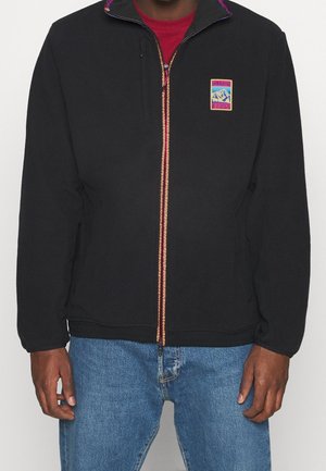 Chaqueta de forro polar negra con cuello alto, cremallera frontal y costuras coloridas. Presenta un pequeño logo de montaña en el lado izquierdo del pecho.