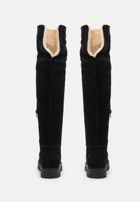 Stivali alti in suede nero con una morbida fodera beige e suole in gomma. Caratterizzati da una cerniera sul lato esterno per una facile calzata.
