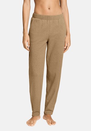 Beige zachte stoffen broek met elastische tailleband en zijzakken gedragen door een blotevoetse persoon, getoond van taille tot voeten.