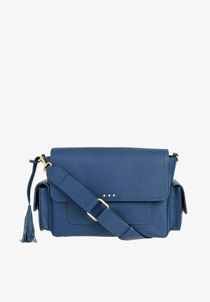 Sac bandoulière en cuir bleu avec fermeture à rabat, sangle réglable, poches latérales, ferrures dorées et un détail de pompon sur un côté.