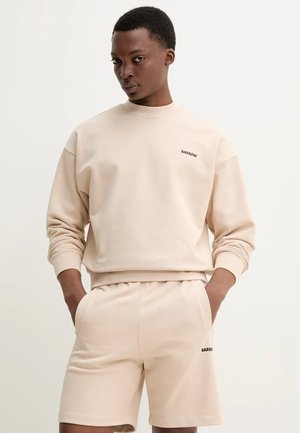 Felpa beige con polsini a coste e logo nero "BARROW", abbinata a pantaloni shorts beige coordinati, con vita elasticizzata e tasche laterali.