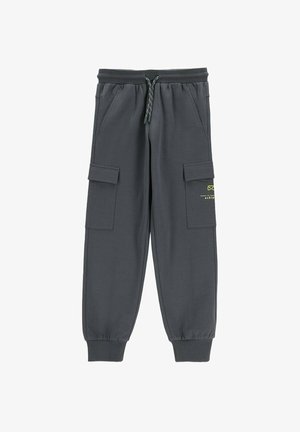 Ciemnoszare spodnie dresowe typu jogger z elastycznymi mankietami, talią na sznurek, bocznymi kieszeniami z klapkami oraz małą żółtą grafiką na prawej kieszeni.