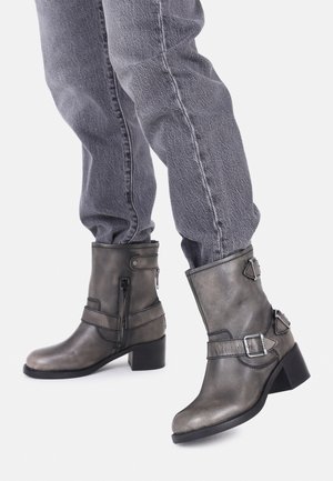 Gray leather ankle boots with a slightly shiny finish, chunkier black heels, side zip, and decorative straps with buckles.
