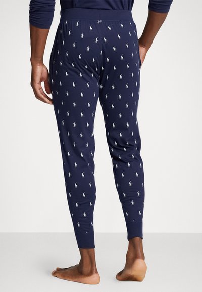 Tumesine pajama püksid, millel on korduv valge polo logo muster, ankletsid ja elastne vöökoht, valmistatud pehmest kangast.