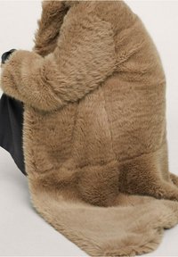 Cappotto in pelliccia sintetica marrone chiaro caratterizzato da un tessuto morbido e testurizzato con un aspetto peloso, design fluido e silhouette leggermente drappeggiata.