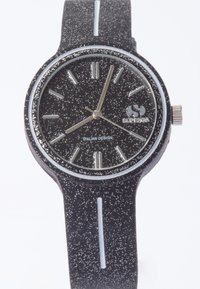 Reloj negro con un diseño salpicado, acentos blancos y hardware plateado. Presenta marcadores de hora alargados y una esfera redonda. Correa ajustable.