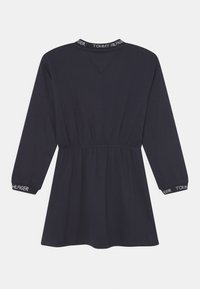 Granatowa sukienka z długimi rękawami, ze zgromadzonym w talii fasonem i logo "TOMMY HILFIGER" na kołnierzu oraz mankietach. Miękka tkanina z luźnym krojem.