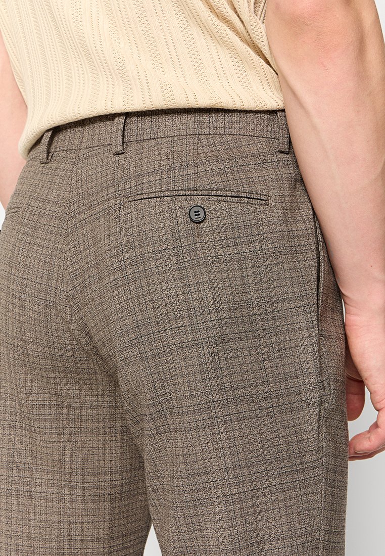 Braune Karohosen aus einem strukturierten Stoff mit einer Gesäßtasche und einem schwarzen Knopf sowie einer taillierten Passform.