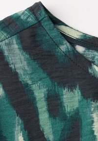 Tessuto texturizzato con una base grigio scuro e motivi astratti in verde e azzurro chiaro, caratterizzato da una scollatura a V e cuciture pulite.