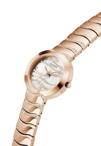 Reloj de oro rosado con caja redonda, esfera de nácar, acentos ondulados y adornos de cristal en la pulsera y la carátula.