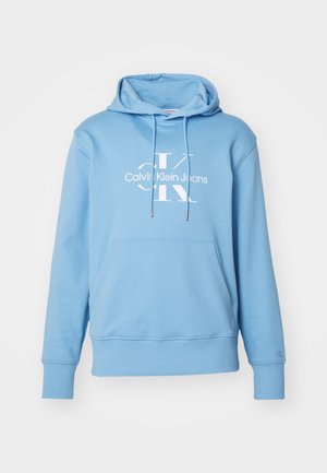 Sweat à capuche bleu clair avec poche avant, cordons et logo blanc "Calvin Klein Jeans" sur la poitrine.