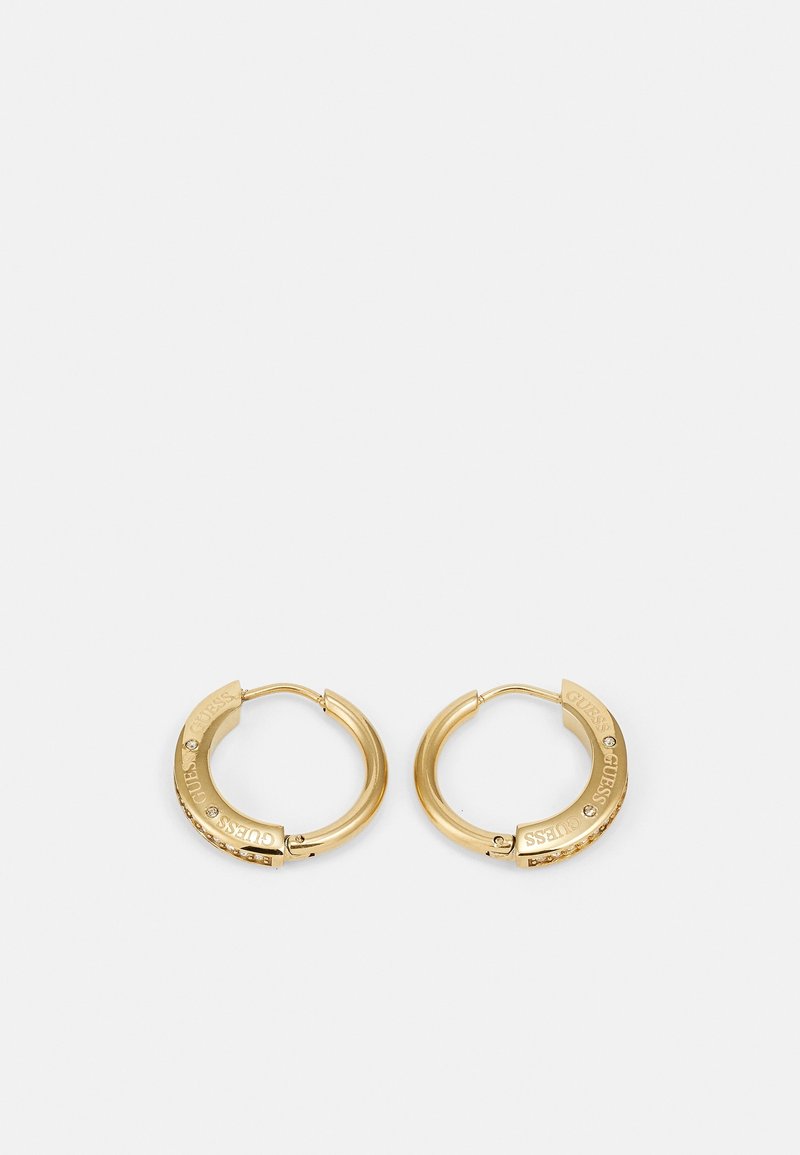 Petites boucles d’oreilles créoles en or avec des cristaux incrustés et le nom de la marque "GUESS" gravé sur la partie avant de chaque créole.