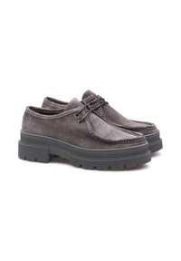 Une paire de chaussures en suède gris à lacets avec de épaisses semelles en caoutchouc noir, des coutures de style mocassin et des semelles extérieures à crampons.
