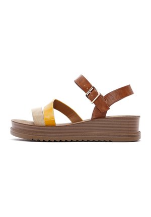 Sandali con zeppa caratterizzati da una fascia in pelle marrone, cinturini incrociati gialli e beige e una suola in gomma marrone testurizzata con un motivo a zigzag.