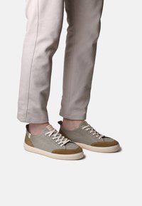 Baskets basses pour hommes en toile grise et vert olive avec des accents en daim beige et un système de laçage, présentant une semelle texturée.