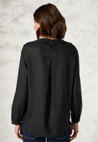 Zwarte blouse met lange mouwen van een gladde stof, heeft een keyhole-opening aan de achterkant en plooidetails, met knoopmanchetten en een ronde zoom.