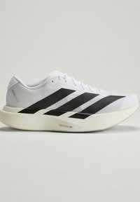 Chaussure de running blanche et noire avec trois bandes noires sur le côté et une semelle épaisse Lightstrike Pro sur un fond uni.