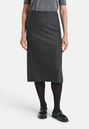 Zwart-wit geblokte rok, knie-lang, gemaakt van gladde stof. Gepaard met zwarte panty en loafers. Eenvoudig, passend ontwerp.