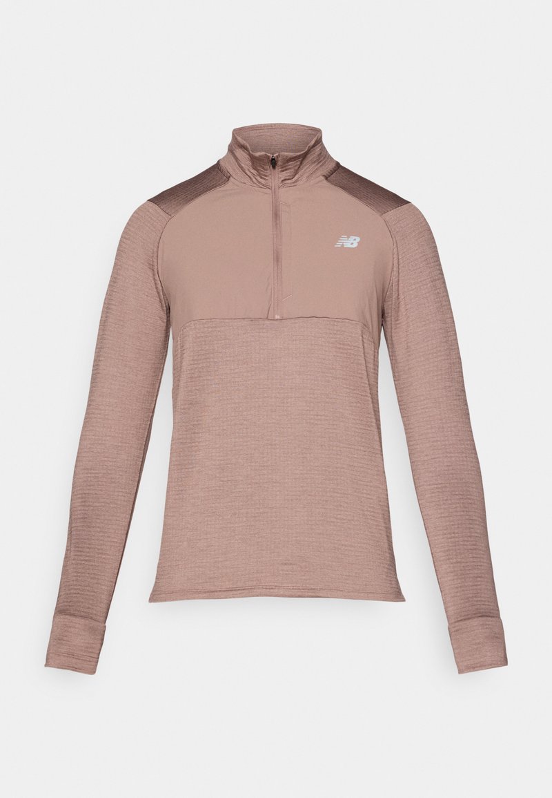Langærmet atletisk top i støvet rose med halvlange lynlås krave, tekstureret stof og mørkere skulderdetaljer. New Balance logo på brystet.