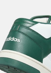 Sneaker in pelle verde con accenti bianchi, suola in gomma strutturata, logo ricamato e dettagli cuciti sulla tomaia.