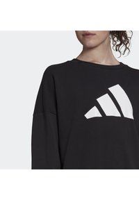 Czarna bluza z okrągłym dekoltem, z dużym białym logo w trzy paski na przodzie. Wykonana z miękkiego materiału o luźnym kroju.