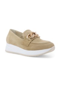 Scarpa slip-on in suede beige con suola piatta bianca. Presenta un nodo decorativo e dettagli in metallo sul davanti. Design con punta arrotondata.