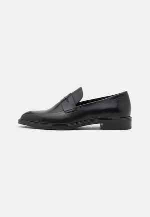 Mocassins en cuir noir avec une finition lisse, bout rond et détail de sangle subtil sur le cou-de-pied, montés sur une semelle basse.