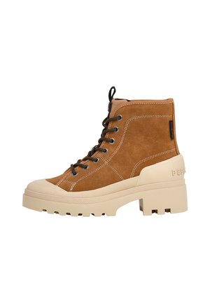 Bruine suède hoge laarzen met een chunky beige zool en contrasterende zwarte veters. Zijaanzicht dat het ontwerp en de textuur benadrukt.
