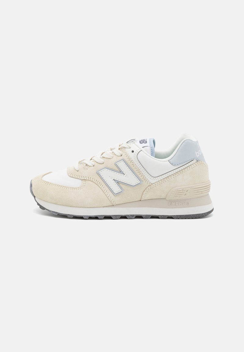 Basket New Balance beige et blanche avec des accents bleu clair, fermeture à lacets et semelle texturée, vue de côté extérieur.
