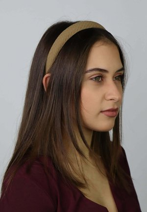 Brązowa teksturowana opaska noszona na długich, prostych włosach; miękkie krawędzie i gładka powierzchnia podkreślają naturalny kolor i styl włosów.