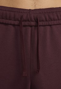 Vinröda joggers med dragsko i midjan, mjukt tyg och ribbstruktur vid midjan för passform och komfort.