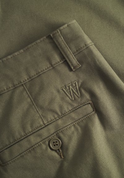 Pantalons vert olive en tissu texturé, dotés d'une fermeture à bouton et d'un logo "W" brodé près de la poche arrière.