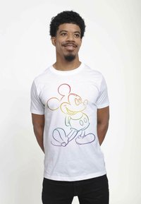 Hvid bomulds t-shirt med en regnbuekontur af en tegnefilmsfigur med store ører, rund krop og store sko. Korte ærmer, rund hals.