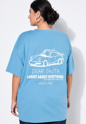 Türkises Baumwoll-T-Shirt mit oversized Passform. Auf der Rückseite befindet sich eine weiße Grafik eines Autos und der Text: "LIEBER CHRISTKIND, VERGISS ALLES."