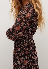 Schwarzes Blumenkleid aus einem durchsichtigen, strukturierten Stoff mit pinken und orangefarbenen Blumen, langen Ärmeln und einem elastischen Taillendesign.