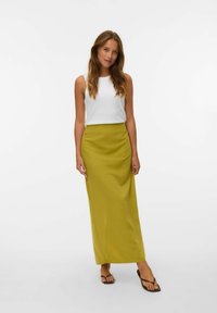 Witte mouwloze top gecombineerd met een lange, limoengroene rok. De rok heeft een gladde textuur en een aansluitende taille, en reikt tot aan de enkels.