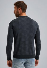 Tmavošedý textúrovaný sveter s dlhými rukávmi, okrúhlym výstrihom a rebrovanými manžetami a lemom. Na zadnej strane výstrihu sa nachádza malý emblém.