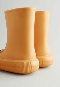 Bottes de pluie en caoutchouc de couleur orange vif avec une finition lisse et texturée et une semelle striée. Tiges droites et talon arrondi pour plus de stabilité.