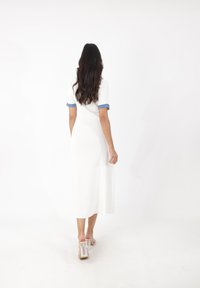 Weißes, geripptes Midikleid mit kurzen Ärmeln aus Denim mit Umschlägen, kombiniert mit klaren Sandalen mit Blockabsatz. Glatte Textur und figurschmeichelnder Schnitt.