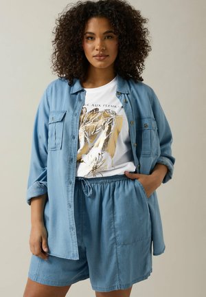 Light blue denim shirt with button closure, paired with a white graphic t-shirt featuring gold accents and matching light blue shorts.